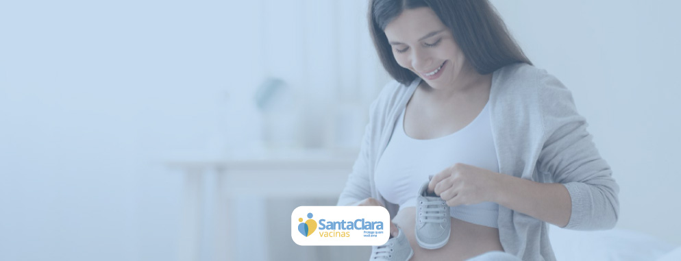 Uma gestante segurando sapatinhos de bebê